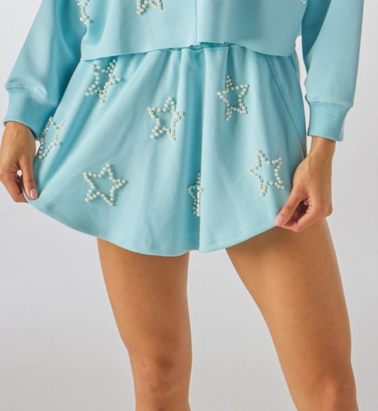 A blue skort with faux pearl outlined star designs, featuring a drawcord elastic waistband.